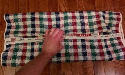 Hand holding plaid fabric over books to make cat scratch board.