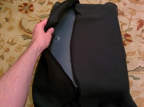 Hand coveres plastic storage bin with black blanket.